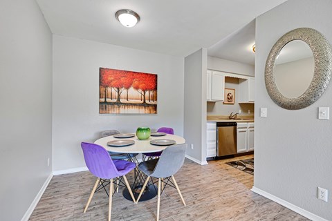 A dining room with a purple chair and a painting of a red forest scene on the wall.