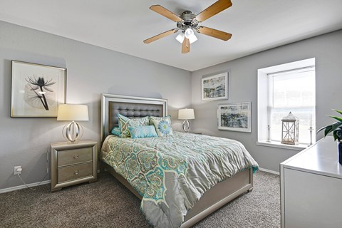 A bedroom with a bed, nightstands, and pictures on the wall.