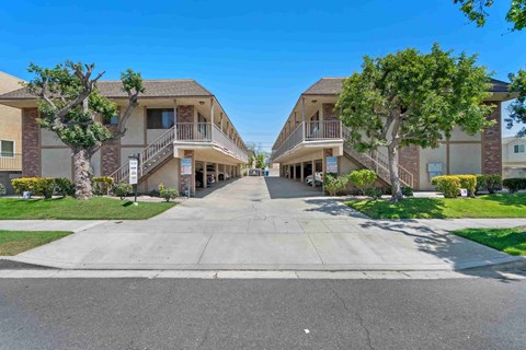 A sunny day at a residential complex with two buildings on either side of a central driveway.