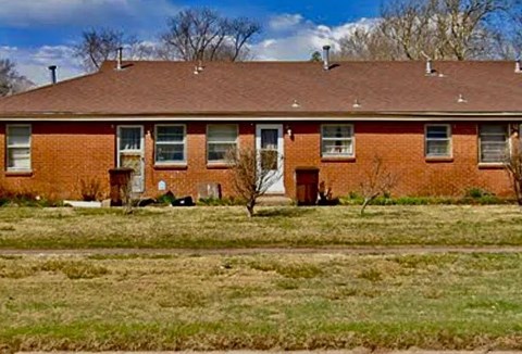 A red brick house with a brown roof and a white door.