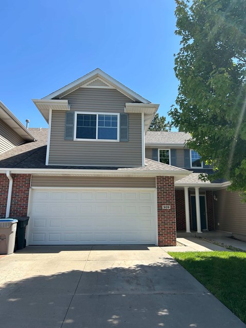 A house with a white garage door and a brick pillar.