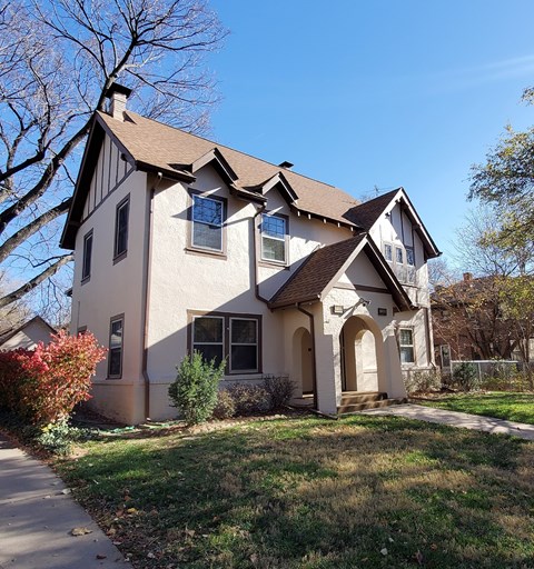 A house with a brown roof and white walls with a small garden in front.