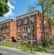 A red brick building with a black fence in front.