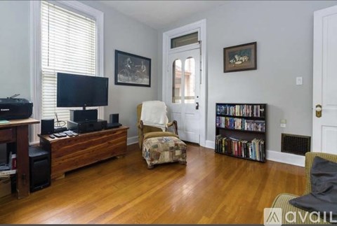 A living room with a white chair and a bookshelf filled with books.