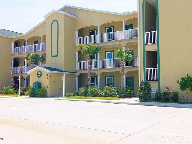 A building with a green door and palm trees in front.
