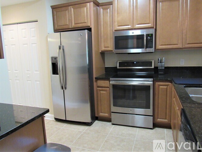 A kitchen with a black counter top and stainless steel appliances.