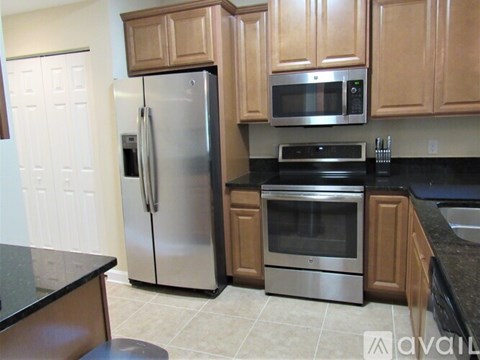 A kitchen with a black counter top and stainless steel appliances.