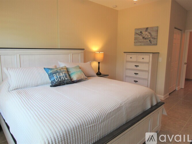 A bedroom with a white bed and a lamp on the side table.