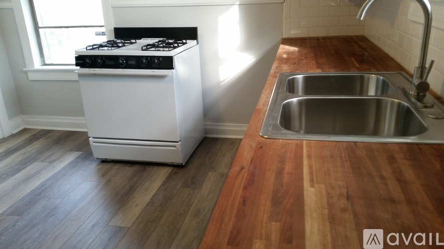 A kitchen with a stove, sink, and wooden floors.