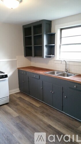 A kitchen with a white dishwasher and dark grey cabinets.