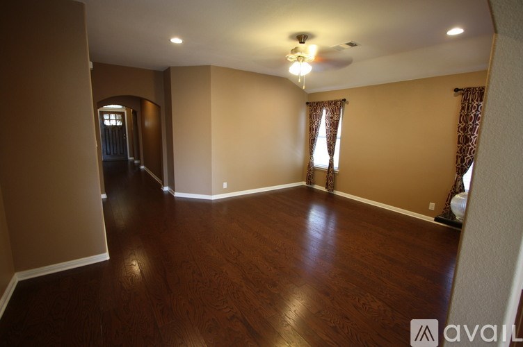 A spacious room with wooden floors and a ceiling fan.