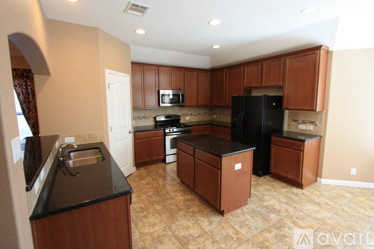 A kitchen with brown cabinets and black countertops.