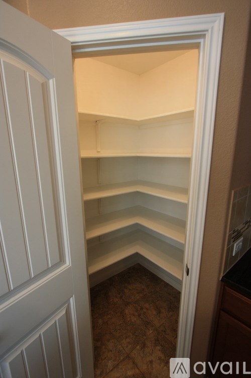 A white door is open to a room with empty shelves.