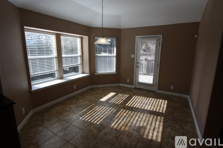 A room with brown walls and a tiled floor with sunlight shining through the windows.