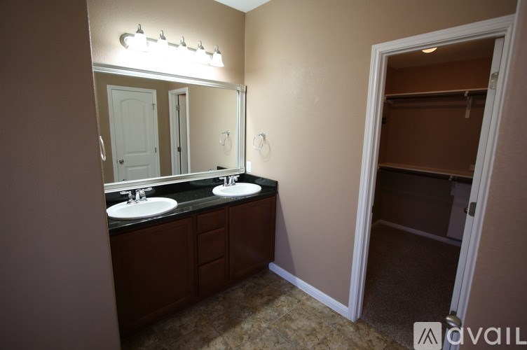 A bathroom with a double sink vanity and a mirror above it.