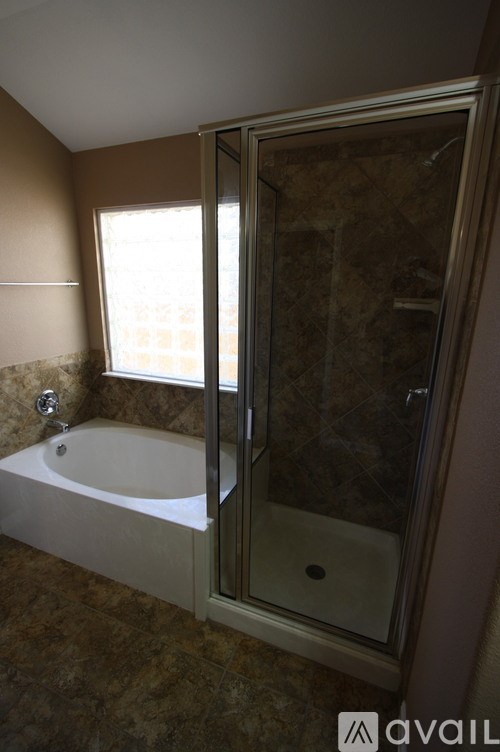 A bathroom with a tiled floor and a bathtub with a shower door.