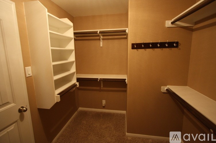 A small, empty closet with a white door and a bench.
