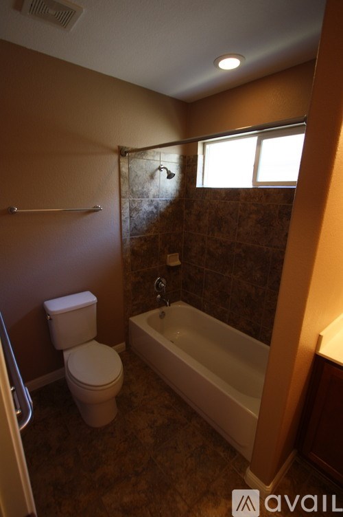 A bathroom with a toilet, bathtub, and a window.