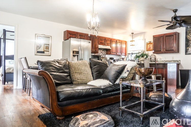A living room with a black leather couch and a chandelier.