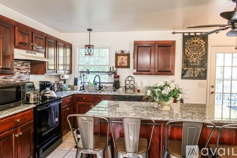 A kitchen with dark wood cabinets and a granite countertop.