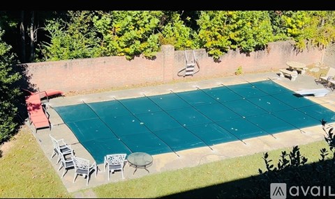 A pool surrounded by chairs and trees.