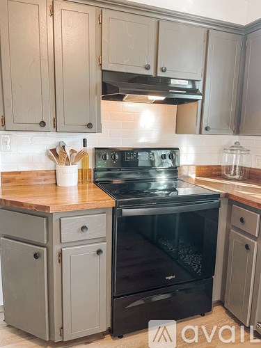 A kitchen with a black stove top oven and wooden countertops.