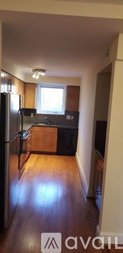 A kitchen with wooden cabinets and a black fridge.