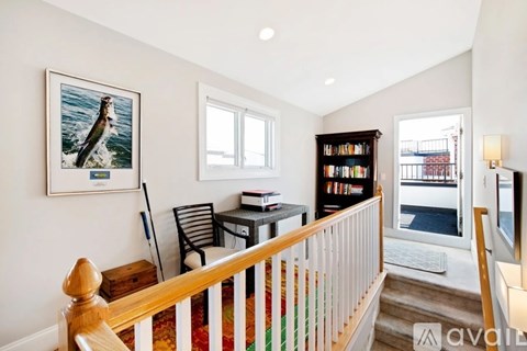 A living room with a bookshelf, a chair, and a painting of a bird on the wall.