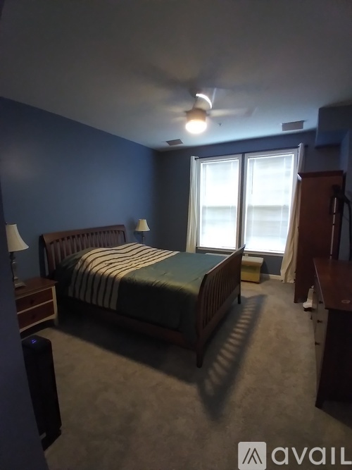 A bedroom with a bed, nightstand, and a ceiling fan.
