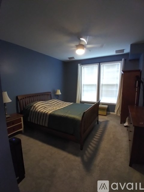 A bedroom with a bed, nightstand, and a ceiling fan.