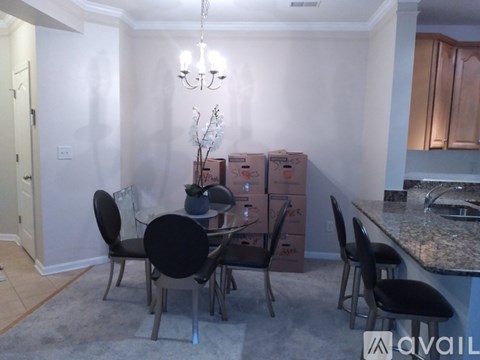 A dining room with a table and chairs and boxes in the background.