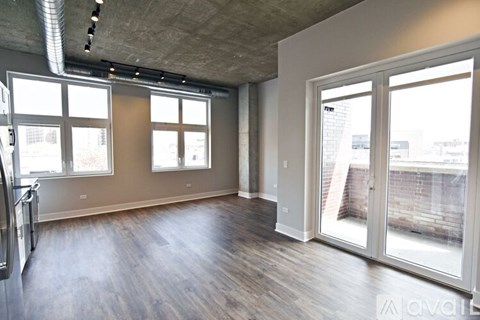 A spacious room with wooden floors and large windows.
