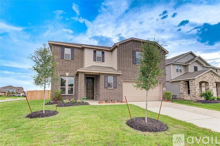 A house with a brown brick exterior and a large front yard with two trees.