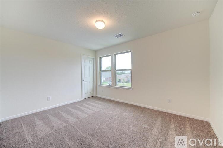 A room with a carpeted floor and a window letting in light.