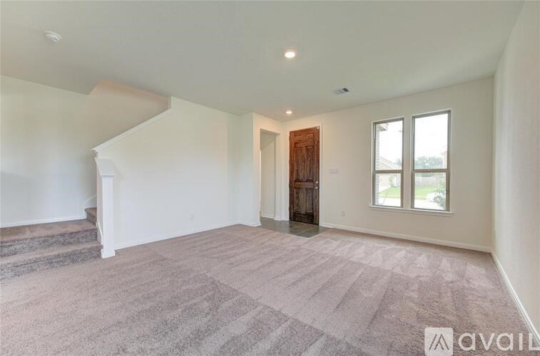 A spacious room with a carpeted floor and a wooden door.