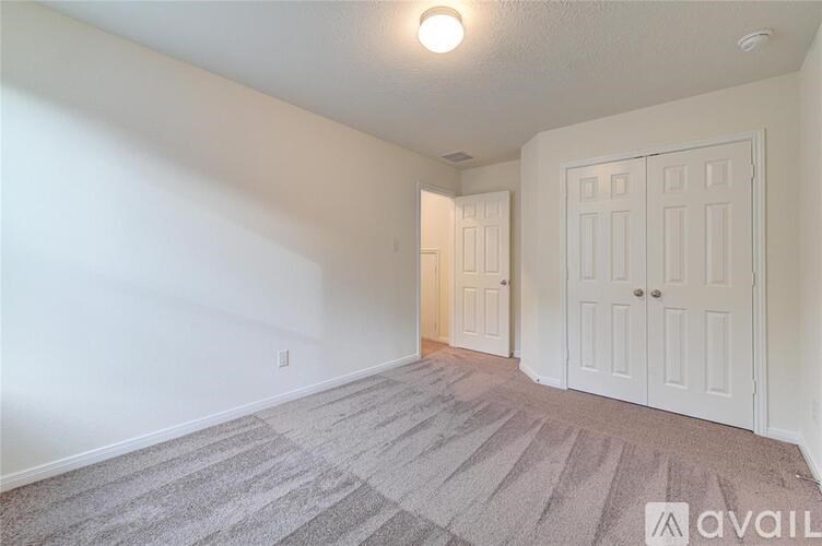 A room with a carpeted floor and two doors.