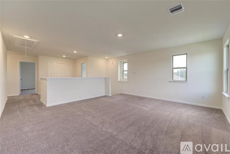 A spacious room with a carpeted floor and a window on the right side.
