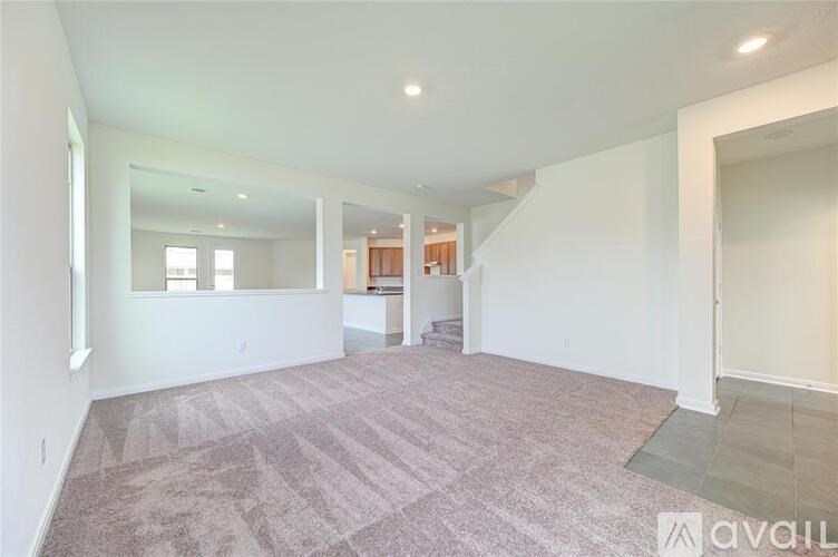 A spacious living room with a carpeted floor and a staircase leading to another room.