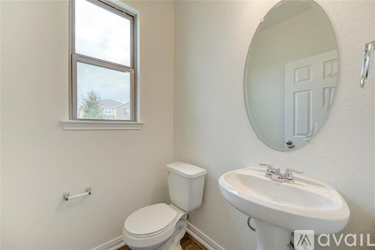 A white toilet and sink in a bathroom with a round mirror.