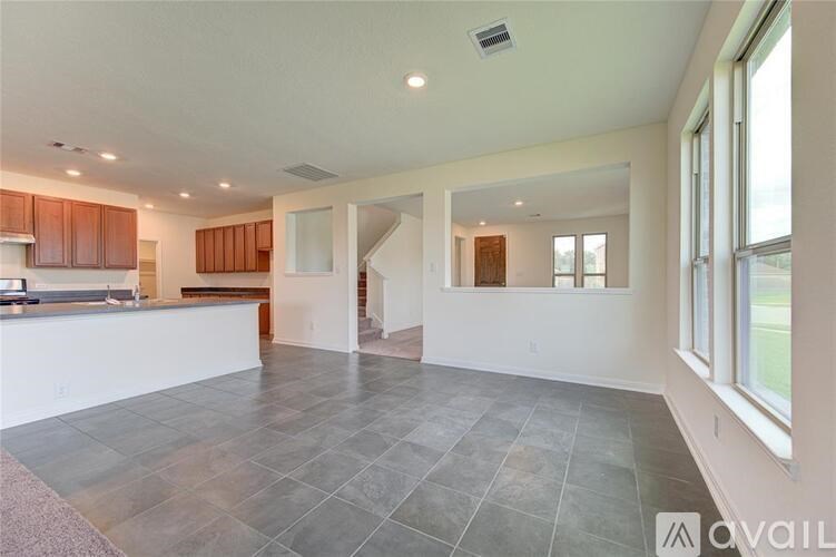 A spacious living room with a kitchen area in the background.
