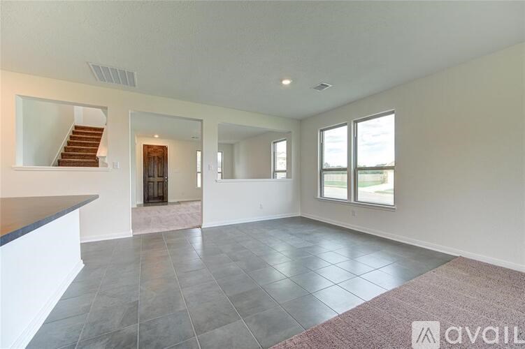A spacious living room with a staircase and large windows.