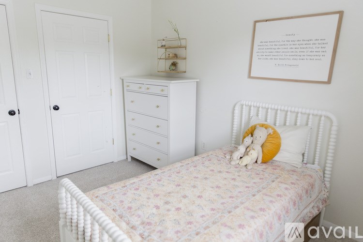 A white bedroom with a floral bedspread and a white bed frame.