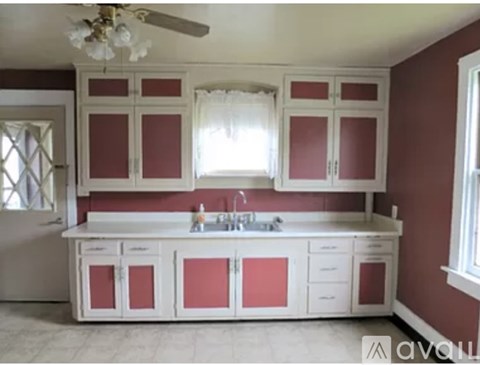 A kitchen with white cabinets and a marble floor.