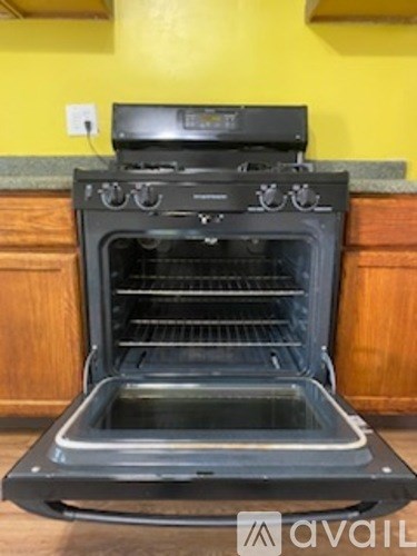 A black oven with the door open is in a kitchen.