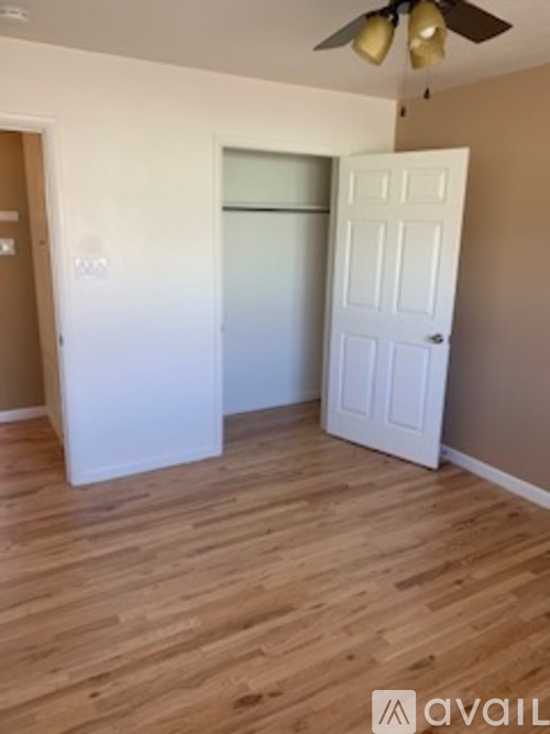 A room with a white door and a ceiling fan.