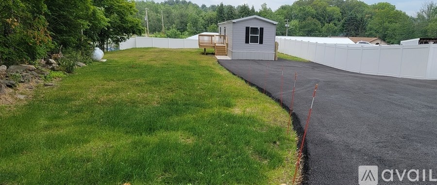 A backyard with a white fence and a small house.