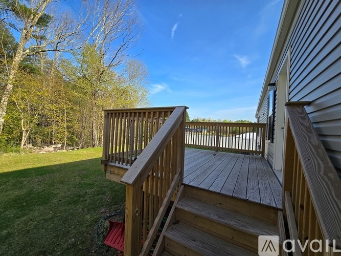 A wooden deck with a red chair and a white house in the background.