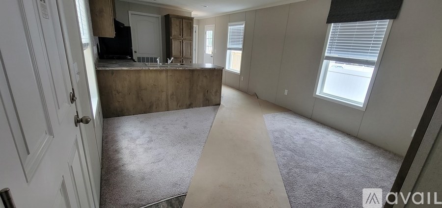 A room with a carpeted floor and a window with blinds.