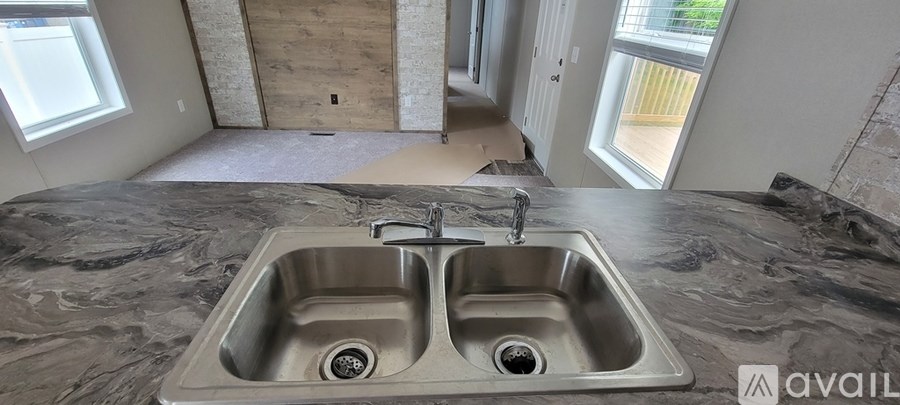 A kitchen under construction with a granite countertop and a double sink.