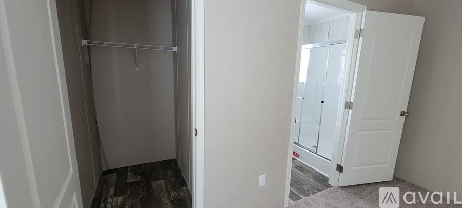 A room with a walk in closet and a doorway leading to another room.